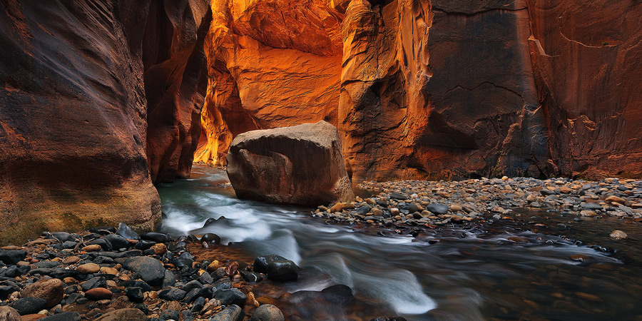 Deep in the Narrows, the Virgin River flows toward the glowing reflected light.